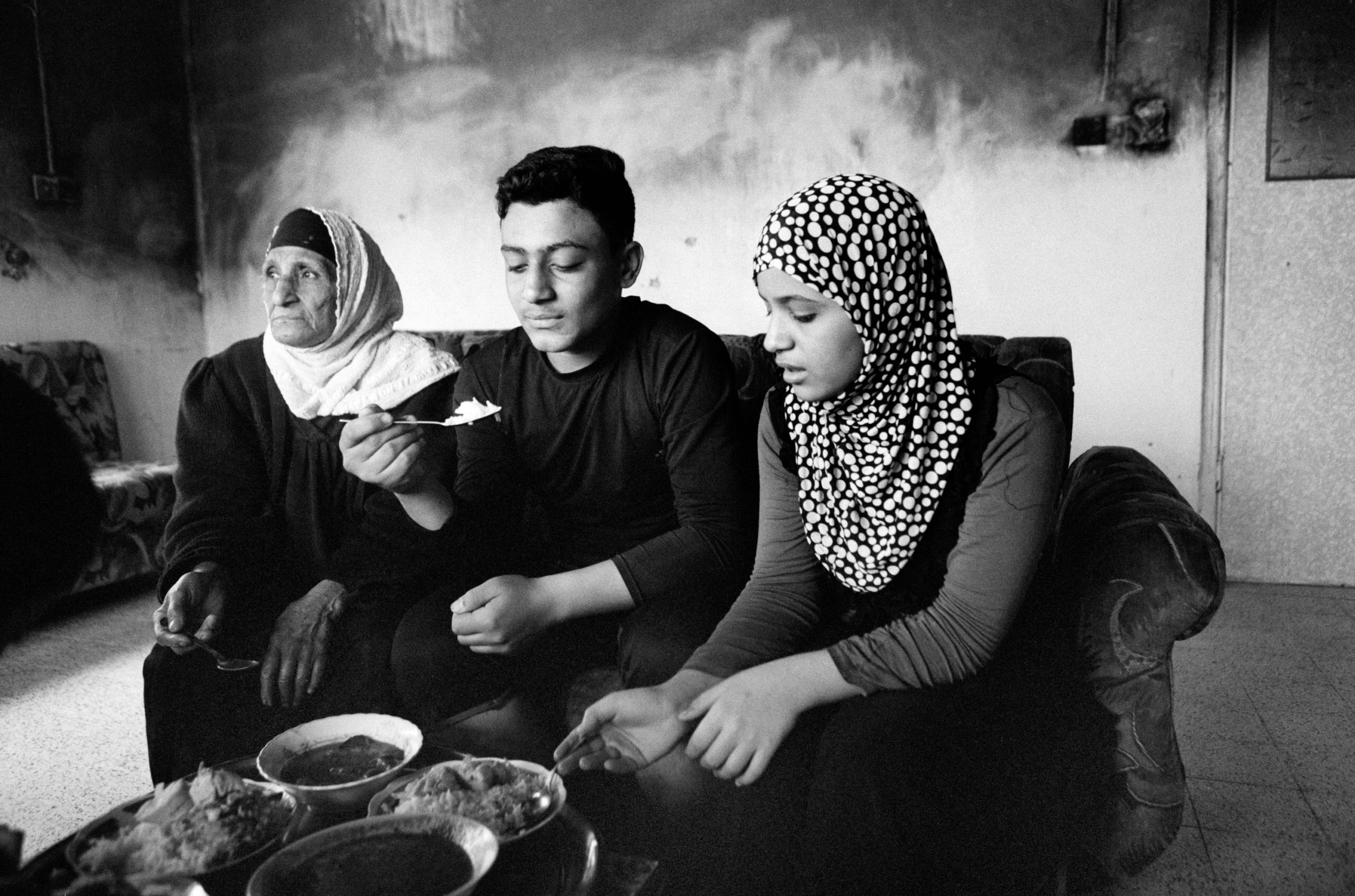 Brother and sister eating food with their grandmother
